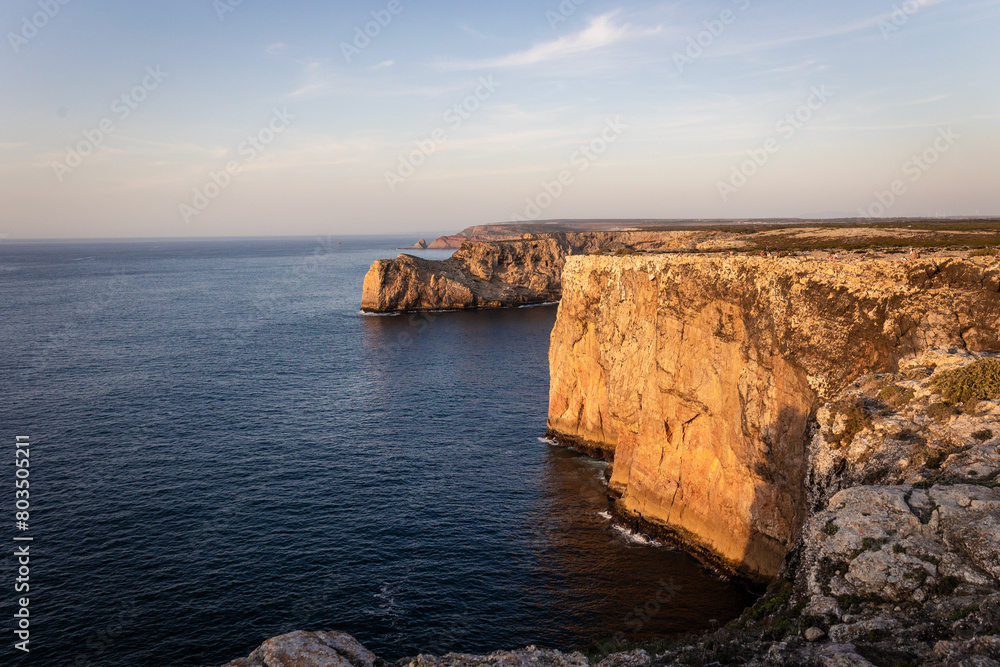 Landscape photo of dramatic, steep orange cliffs by the atlantic at sunset. Shot in Farol fo Cabo de Sao Vincente near Sagres, Portugal. Landscape photo of dramatic, steep orange cliffs by the atlantic at sunset. Shot in Farol fo Cabo de Sao Vincente near Sagres, Portugal.