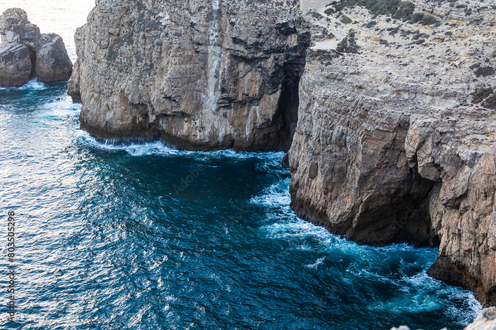 Obraz premium Landscape photo of dramatic, steep orange cliffs by the atlantic at sunset. Shot in Farol fo Cabo de Sao Vincente near Sagres, Portugal.