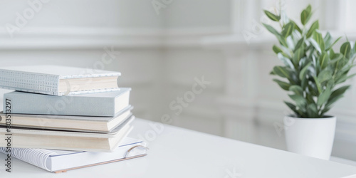 A simple yet impactful photo of stack of books and planners positioned neatly on a white elegant teacher's table, symbolizing the essence of back to school readiness and the import