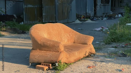 Forgotten Urban Squalor: Discarded Couch Among Slum Shanties at Sweltering Summer Sunset photo