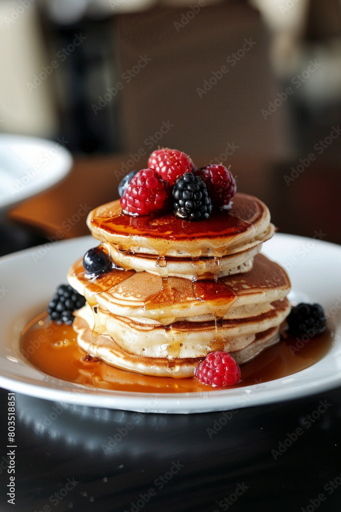 Stack of pancakes with maple syrup and berries