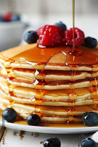 Stack of pancakes with maple syrup and berries