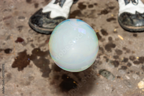A Bubble Filled with Smoke Hovers Above the Floor, Against a Background of Blurry Clown Shoes, Creating an Ethereal and Mysterious Scene