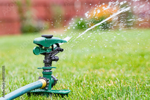 Foto Lawn sprinkler watering grass in yard