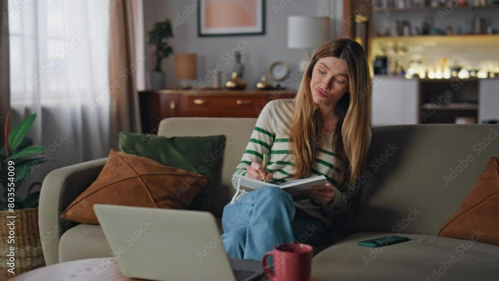 Girl writing online course looking laptop at home couch. Student listening video Girl writing online course looking laptop at home couch. Student listening video