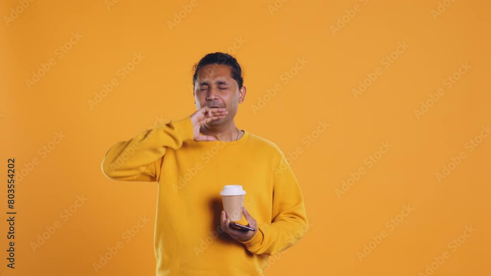 Indian man enjoying coffee from disposable paper cup and send text messages on smartphone. Person drinking hot beverage and chatting with friends on mobile phone, studio background, camera B Indian man enjoying coffee from disposable paper cup and send text messages on smartphone. Person drinking hot beverage and chatting with friends on mobile phone, studio background, camera B