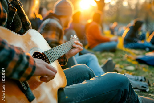 Young man playing guitar with friends attend a live music event concert in a park