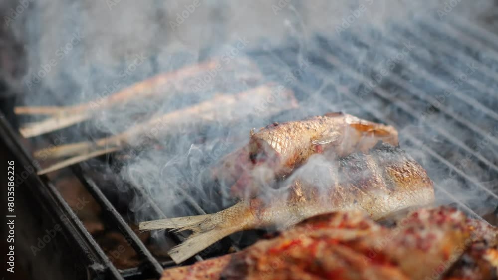 Close-up shot of cooking fish. Baking and roasting marinated fish on barbecue grill. Sea bass or grouper grilled over charcoal. 4K
Close-up shot of cooking fish. Baking and roasting marinated fish on barbecue grill. Sea bass or grouper grilled over charcoal. 4K