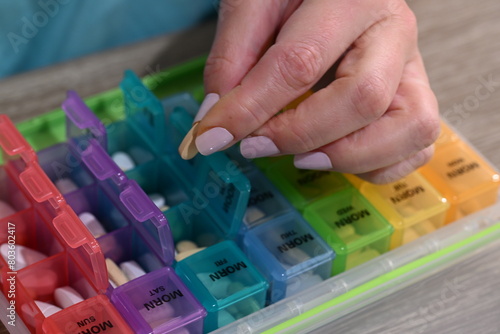 middle age hands load colorful monthly reminder pill box photo