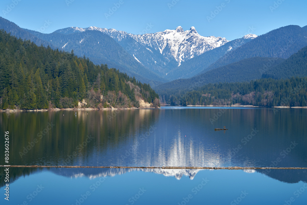 Capilano Lake Lions Peaks Reflection North Vancouver. The view of the Lions high over the Capilano Lake Reservoir in Capilano River Regional Park, North Vancouver, British Columbia.

