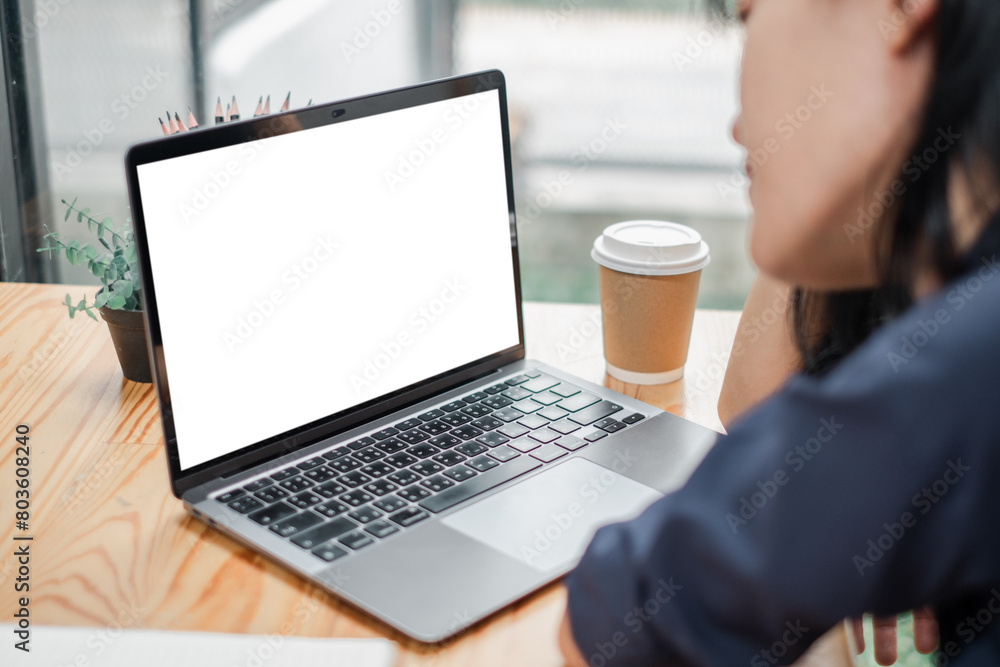 Businesswoman focused on a blank screen laptop in a modern workspace with a coffee cup. Businesswoman focused on a blank screen laptop in a modern workspace with a coffee cup.