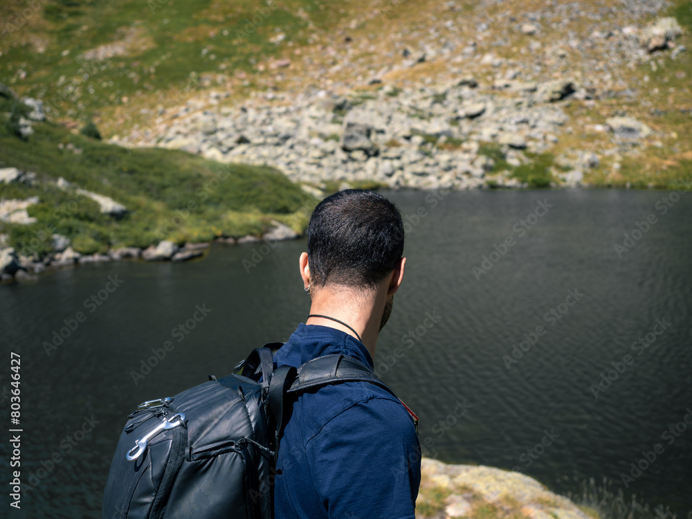 Man with a Backpack Overlooking Tranquil Mountain Lake