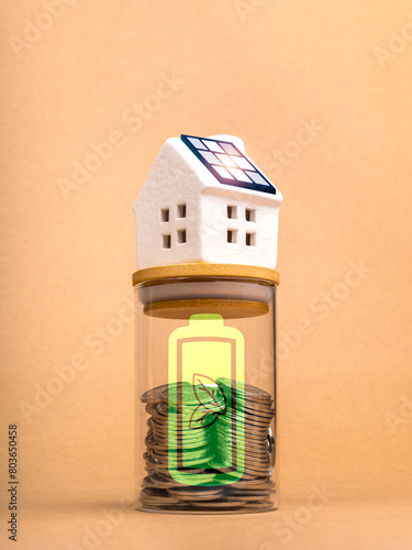 Sustainability at home, savings, environment responsibility concepts. Solar cell panel on white house on money coin bottle with green energy battery icon on recycle paper background, vertical style.