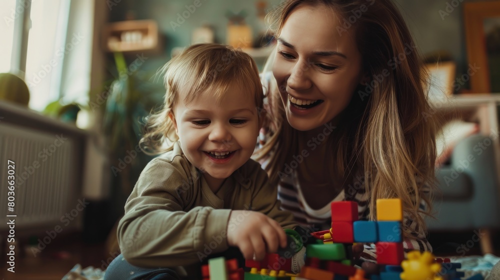 A woman and a child are playing with a pile of colorful blocks. Scene is happy and playful