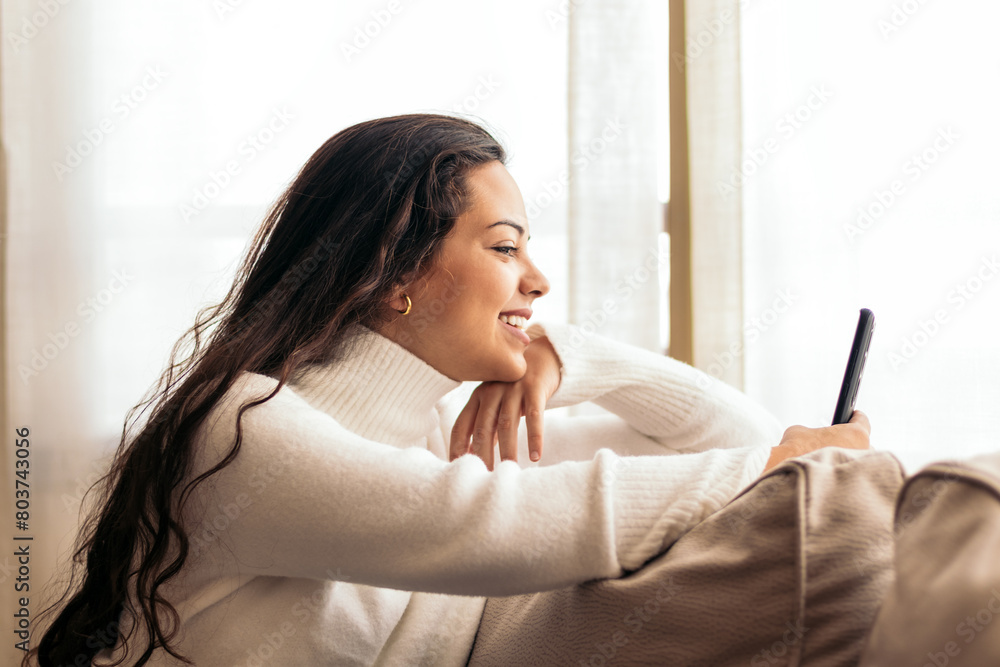 Connected at Home: Young Woman Sitting on Sofa Using Smartphone Connected at Home: Young Woman Sitting on Sofa Using Smartphone