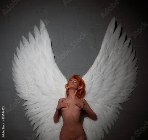 Naked female angel with white angel wings ready to ascend