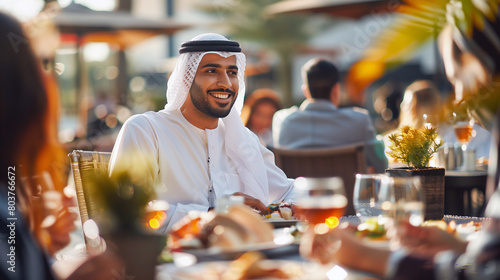 Arab Middle Eastern man in Kandura Ghutra having meeting or launch out with colleagues workmates coworkers. Emirati UAE national at an outdoor restaurant in Dubai. photo