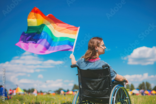 Disabled woman in wheelchair at a summer festival event on blue sky sunny day. Gay lesbian female with disability at pride parade