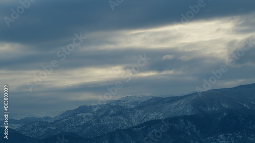 Enveloping Misty Clouds Over Snowcapped Mountains. Mountain Peak Covered With Snow On Cloudy Day. Timelapse.