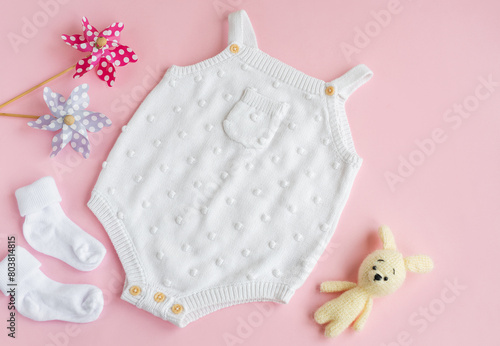 Set of white clothes and accessories for newborn baby. Knitted toys, knitted romper, socks