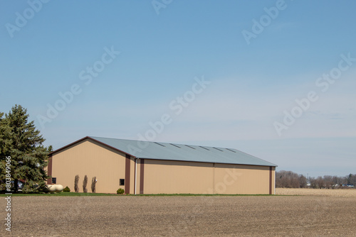 A large farm building next to a corn field. © Romar66