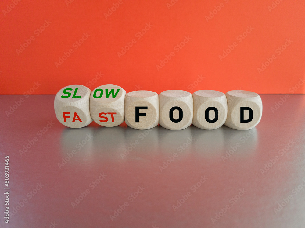 Turned wooden cubes and changes red word fast food to slow food. Beautiful grey table, red background Turned wooden cubes and changes red word fast food to slow food. Beautiful grey table, red background