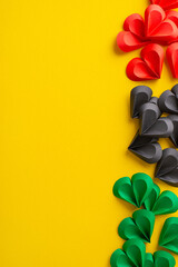 Vertical array of red, black, and green paper hearts arranged artistically on a yellow surface reflecting the themes of unity and celebration for Juneteenth