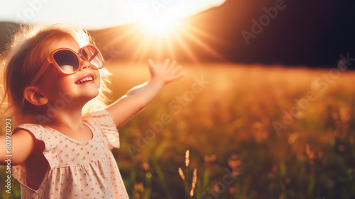 Happy little girl with sunglasses looking at the sun photo