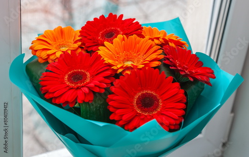 A bouquet of gerbera flowers in close-up on the background of a window