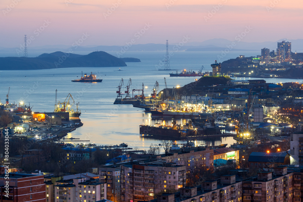 Vladivostok city, Primorsky Krai, Far East of Russia. Evening view of Diomede Bay and the Eastern Bosphorus Strait. There are many ships at the piers in the sea bay. Icebreaker in the distance.
