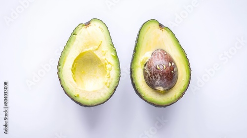 Two halves of an avocado, one with the pit, arranged neatly on a bright white surface, emphasizing freshness and simplicity