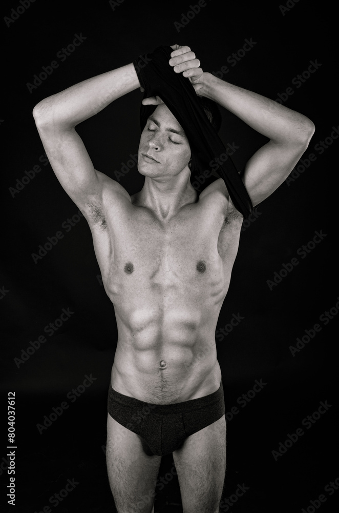Naklejka premium A young attractive man with a beautiful body posing in the studio.