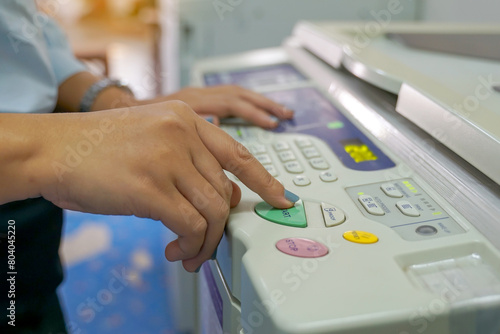 Photography The office secretary presses the button to start the document copying machine to have another copy of the document stored in a file as evidence