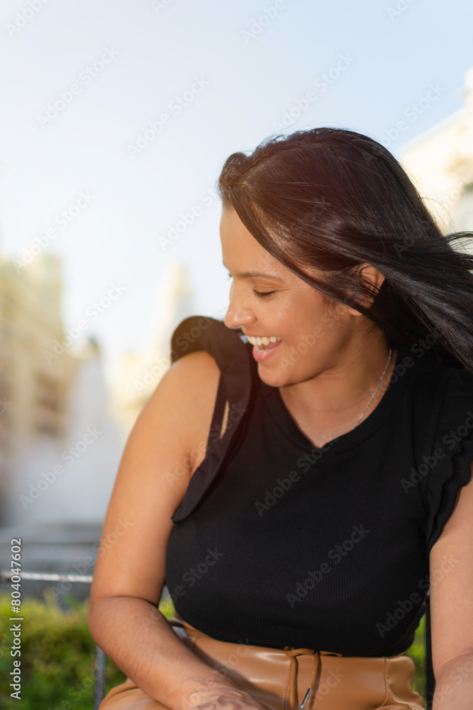 A young Hispanic woman smiling in the warm evening light with an urban background A young Hispanic woman smiling in the warm evening light with an urban background