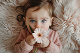A portrait of a cute baby holding a flower. Mothers day gift