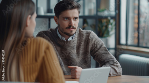  Handsome young male employer talking to female professional candidate on job interview, discussing resume. Boss and manager discussing work plan, strategy, sales report at meeting table