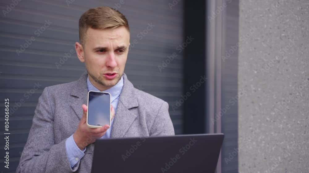 Businessman talking on the mobile phone, holding laptop outdoors. Slow motion Businessman talking on the mobile phone, holding laptop outdoors. Slow motion