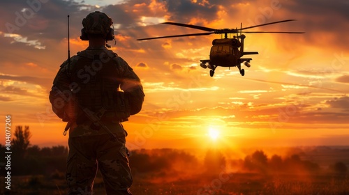 Memorial Day, A soldier stands in the field at sunset as a helicopter approaches. photo