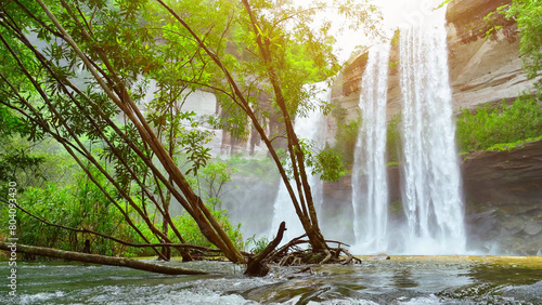 Jaw-dropping waterfall cascading from towering cliff, embraced by vibrant tropical greenery. Huai Luang Waterfall, Phu Chong Na Yoi national park, Ubon Ratchathani Province, Thailand. Travel concept.
 photo