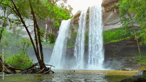 A majestic waterfall cascades from a towering cliff  enveloped by vibrant tropical foliage  creating a breathtaking natural spectacle. Huai Luang Waterfall  Thailand. Explore world s wonders concept. 