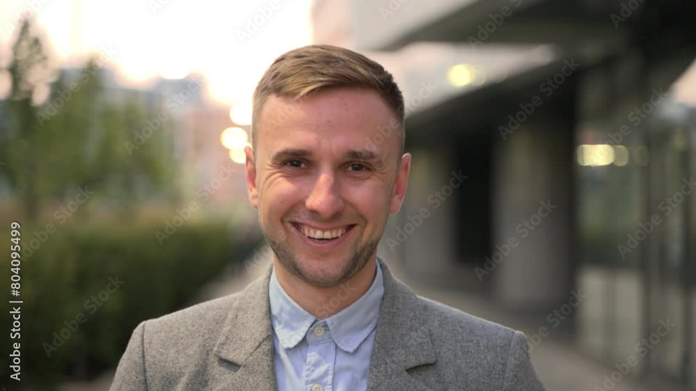 Smiling young businessman looking at camera in the city. Slow motion Smiling young businessman looking at camera in the city. Slow motion