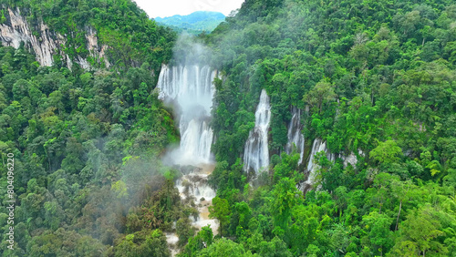 Aerial perspective unveils a breathtaking spectacle - a magnificent waterfall concealed within the heart of a dense rainforest, nature's beauty hidden in plain sight. Wild woods: Earth's sanctuary.
