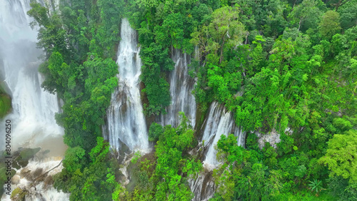 Through the drone s lens  the heart of the tropical rainforest unveils a mesmerizing secret - a majestic  secluded waterfall  framed by an emerald sea of dense greenery. Raw forest  pure wonder.  