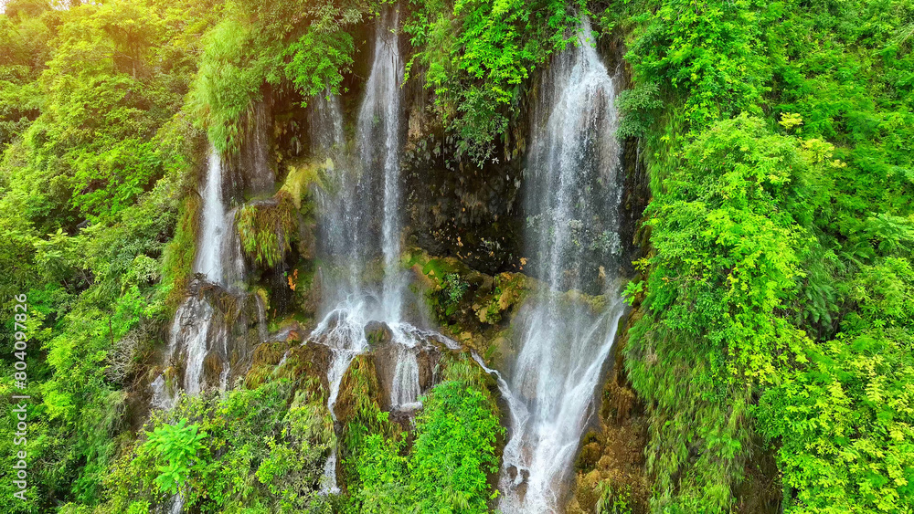 Obraz premium Nature's Hidden Wonder: From above, witness the breathtaking allure of a mystical waterfall concealed amidst the vibrant, green heart of the jungle. Oasis paradise woods. Thailand.