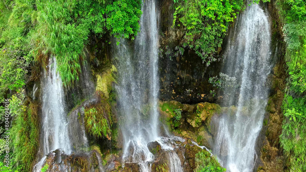Jungle gem: Discover the enchanting allure of a triple waterfall concealed within the depths of a tropical jungle. A drone's eye view reveals the beauty hidden beneath the canopy. Thailand.
