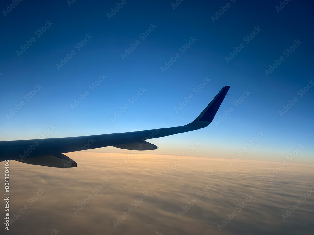 View from airplane window. Airplane wing in the blue sky above the clouds. View from airplane window. Airplane wing in the blue sky above the clouds.