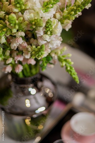 bouquets of flowers are on the table, a tray with a cup and a glass of water