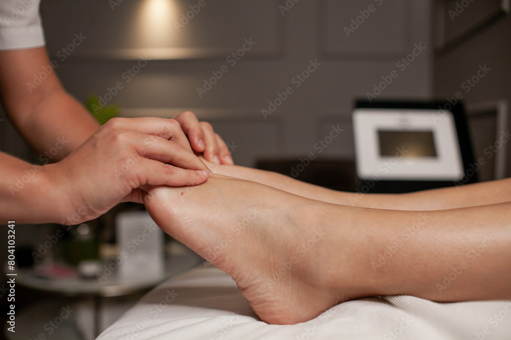 Massage therapist doing foot and leg massage with hands