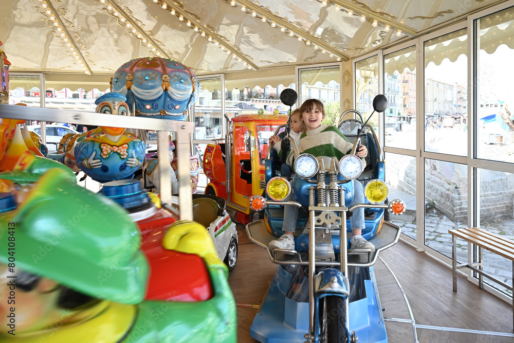 two children playing on a motorcycle in a merry-go-round two children playing on a motorcycle in a merry-go-round