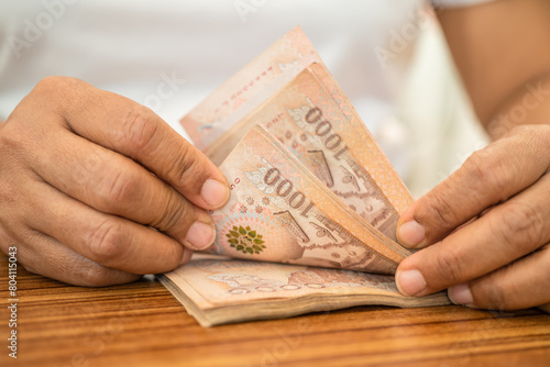 Asian business woman holding Thai banknote currency money.